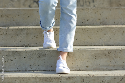 Billede på lærred Woman legs wearing sneakers walking down stairs
