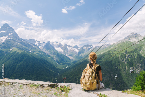 Child traveler sitting on mountain by cableway and enjoying beautiful summer view.