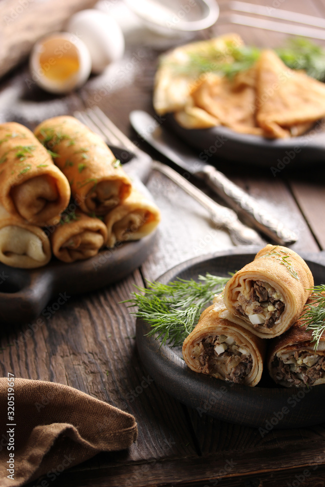 Concept of Russian cuisine. Pancakes with meat on a dark wooden background Concept of Russian cuisine. Pancakes with meat on a dark wooden background