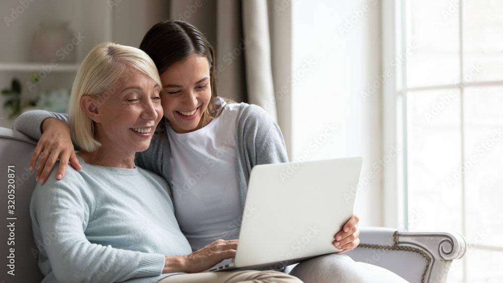 Happy senior mother and adult daughter using laptop together Happy senior mother and adult daughter using laptop together