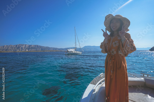 Marseille, France - August 13th, 2019:A young woman is enjoying sunshine and beautiful view in Calanques de Morgiou, Marseilles, Provence, South of France.  She looks very cheerful and happy.