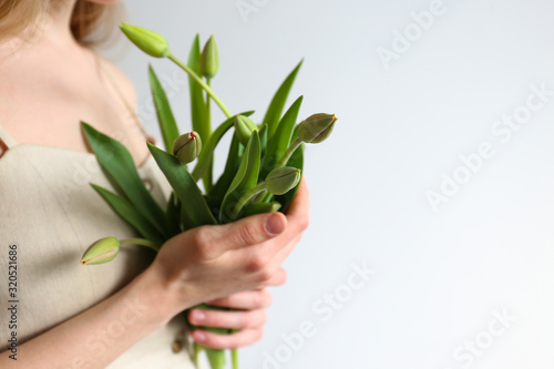 Conceptual image of a woman holding spring flowers as present for international women's day. Close up, copy space, background.