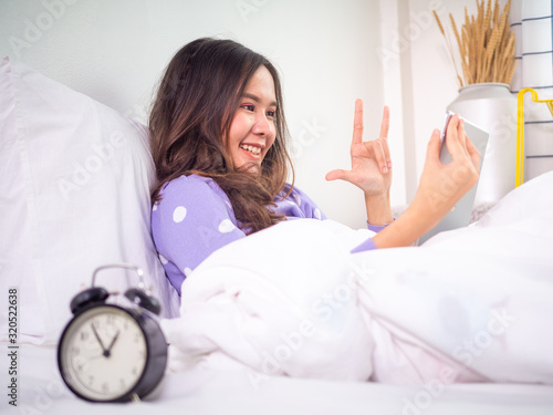 A woman is addicted to a smartphone to video chat with her boyfriend until late at bedtime.
