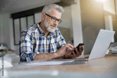 Man working from home with laptop and smartphone photo