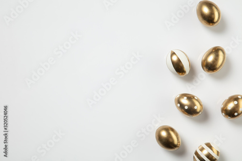 Egg hunt is coming. Easter traditions, golden colored eggs on white background, top view, copyspace for your ad or greetings. Concept of holidays, spring, celebrating, food and sweets, family time.
