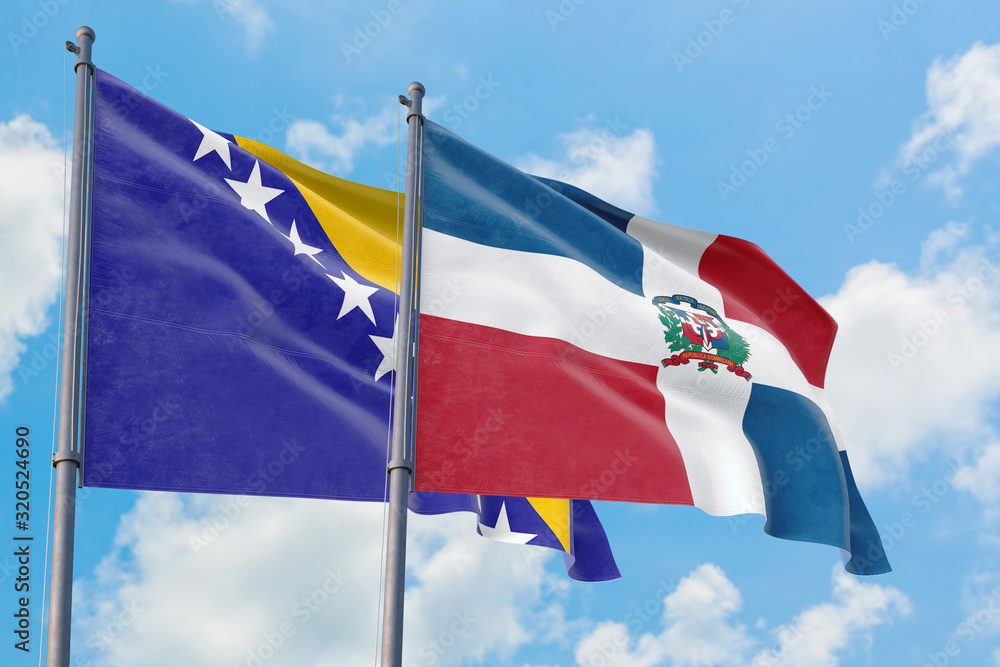 Dominican Republic and Bosnia Herzegovina flags waving in the wind against white cloudy blue sky together. Diplomacy concept, international relations. Dominican Republic and Bosnia Herzegovina flags waving in the wind against white cloudy blue sky together. Diplomacy concept, international relations.