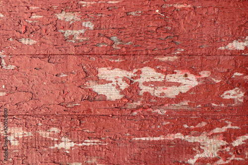 The peeling paint on the wooden surface is brown and red.