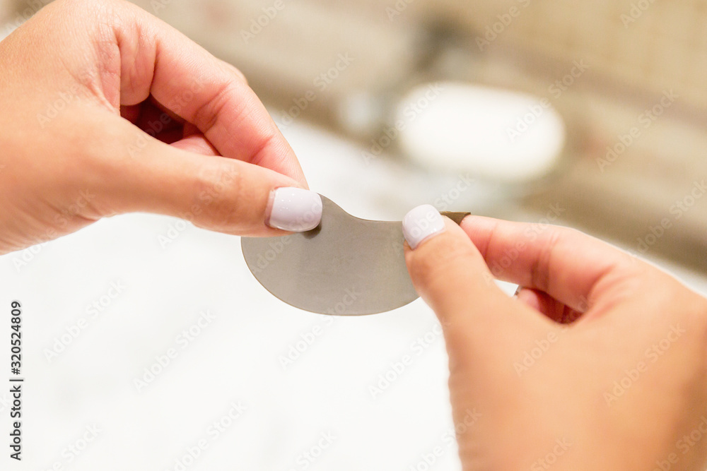 Crop image of female hands holding an eye patch and getting ready to apply it in the morning. Remove your dark circles under eyes Crop image of female hands holding an eye patch and getting ready to apply it in the morning. Remove your dark circles under eyes