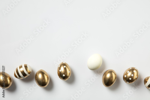 Egg hunt is coming. Easter traditions, golden colored eggs on white background, top view, copyspace for your ad or greetings. Concept of holidays, spring, celebrating, food and sweets, family time.