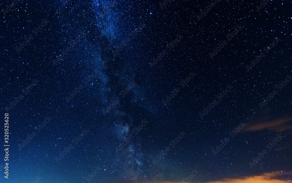 Fototapeta premium Magiczna gwiaździsta noc nad brzegiem rzeki z dużym drzewem i drogą mleczną na niebie i spadającymi gwiazdami latem.