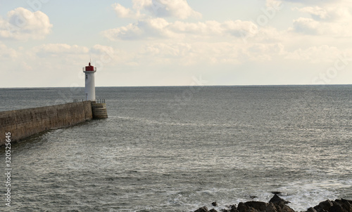 Audierne ville du Finistère en Bretagne sa baie son phare sa jetée le pont et les vagues qui se jettent sur les rochers en projetant de l'écume à marée haute