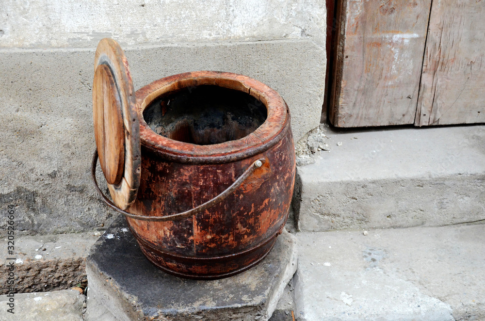 An old Chinese toilet stands against the old wall to dry An old Chinese toilet stands against the old wall to dry