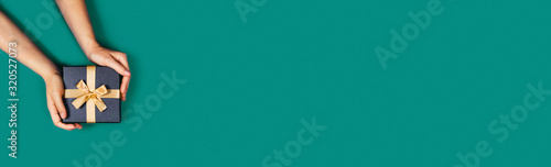 Gift box with surprise in a female hands on green background. Flat lay, top view, place for text.