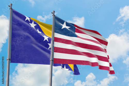 Liberia and Bosnia Herzegovina flags waving in the wind against white cloudy blue sky together. Diplomacy concept  international relations.
