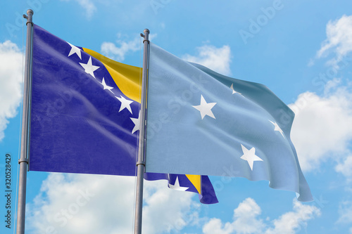 Micronesia and Bosnia Herzegovina flags waving in the wind against white cloudy blue sky together. Diplomacy concept, international relations.