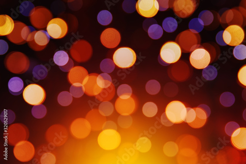 Yellow, purple, orange and red bokeh on a dark background. Beautiful blurry circles. Holiday lights.