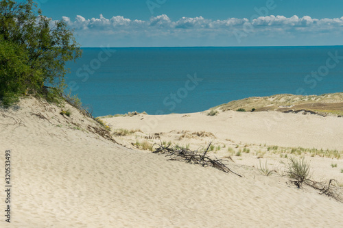 Landscape of sandy beach with sand dunes  sea  and cloudy sky