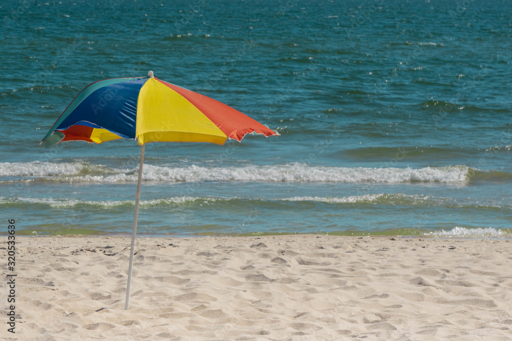 Colorful beach umbrella on tropical beach and sea with waves in background
