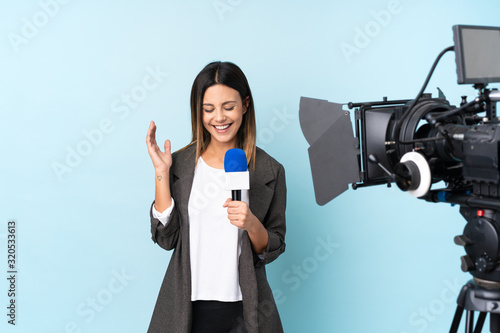 Photography Reporter woman holding a microphone and reporting news over isolated blue backgr