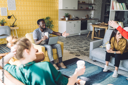 Фотография Cheerful multiethnic friends with drinks at home