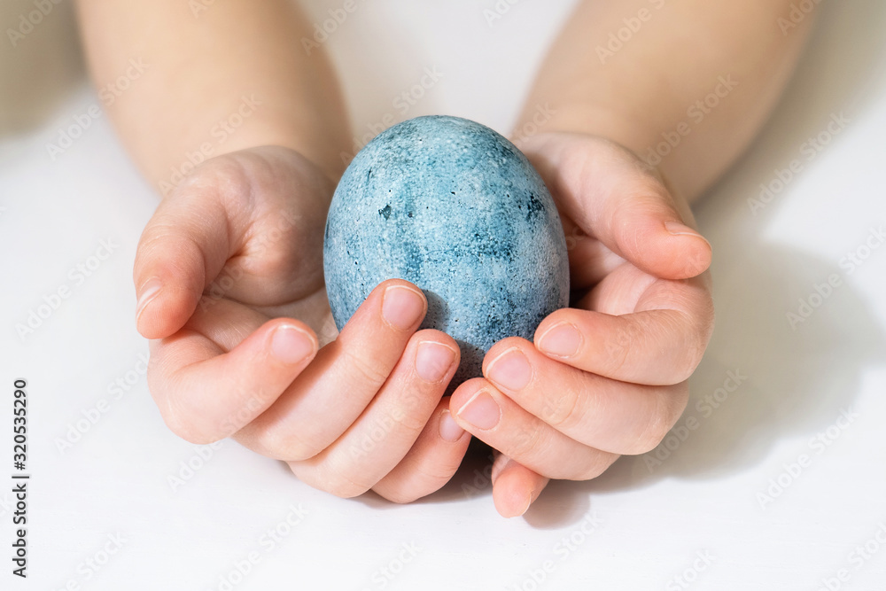 Children's hands are holding an Easter egg. Beautiful egg painted for Easter. Close up of a blue egg Children's hands are holding an Easter egg. Beautiful egg painted for Easter. Close up of a blue egg