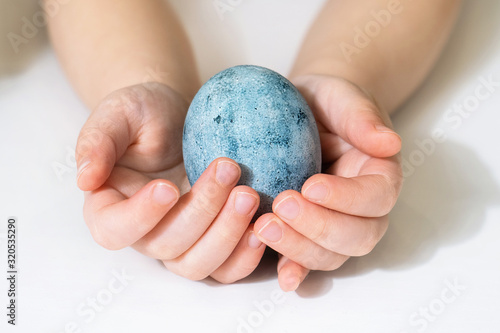 Children's hands are holding an Easter egg. Beautiful egg painted for Easter. Close up of a blue egg © Надин Стокер