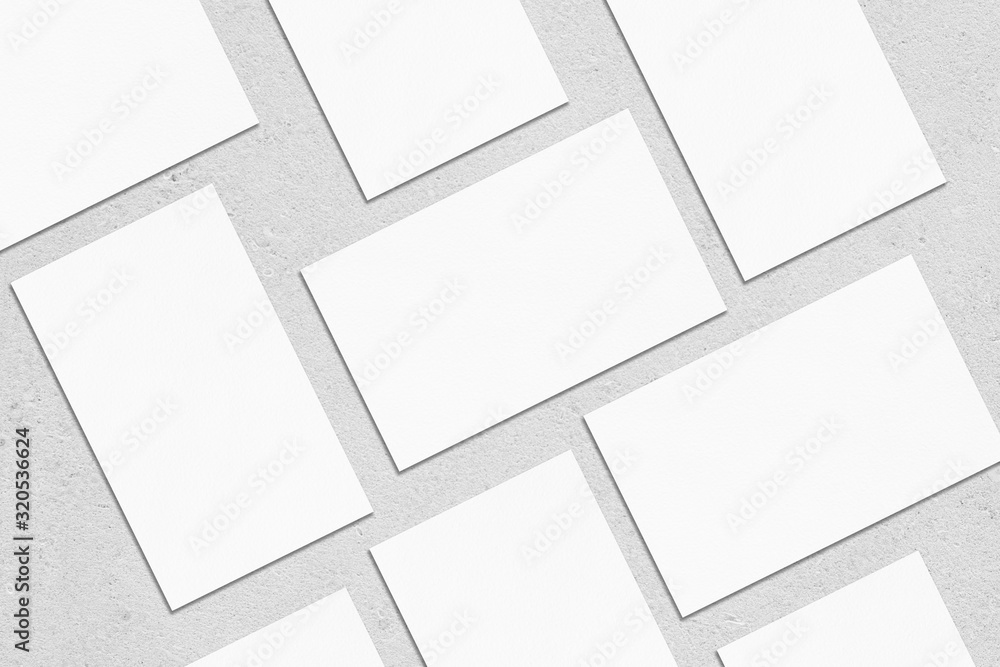 Closeup of empty white rectangle business card mockups lying diagonally on neutral grey concrete background. Flat lay, top view. Open composition. Blank Template for Corporate Identity. Copy space Closeup of empty white rectangle business card mockups lying diagonally on neutral grey concrete background. Flat lay, top view. Open composition. Blank Template for Corporate Identity. Copy space