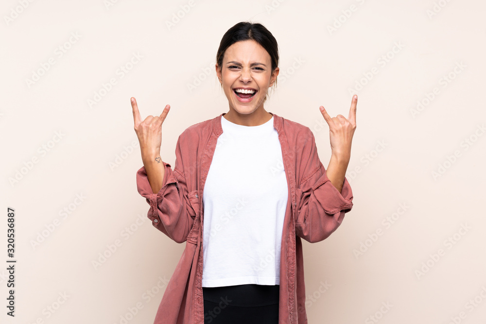 Woman over isolated background making rock gesture Woman over isolated background making rock gesture
