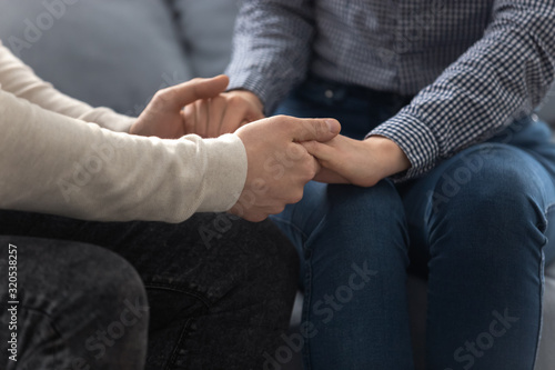 Closeup view loving couple seated together on couch holding hands