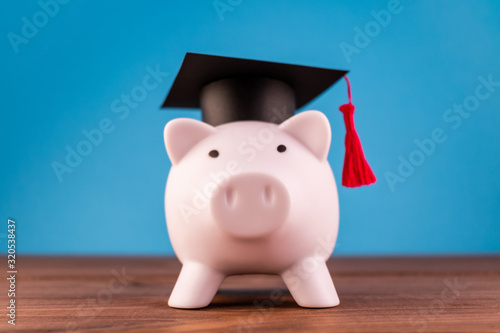 Piggy bank with a graduation hat on a light blue backround. Student scolarship save concept. Finance concept.
