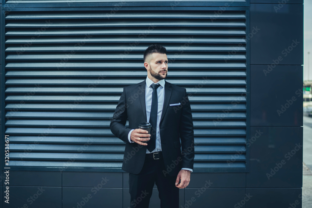 Bearded entrepreneur with beverage to go standing on street