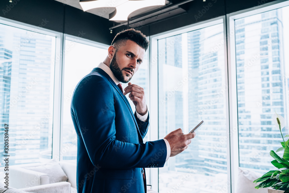 Fototapeta premium Overworked male office employee in suit using smartphone