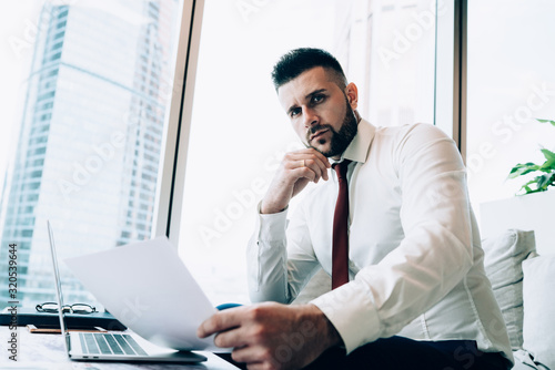 Confident businessman checking paperwork in office space