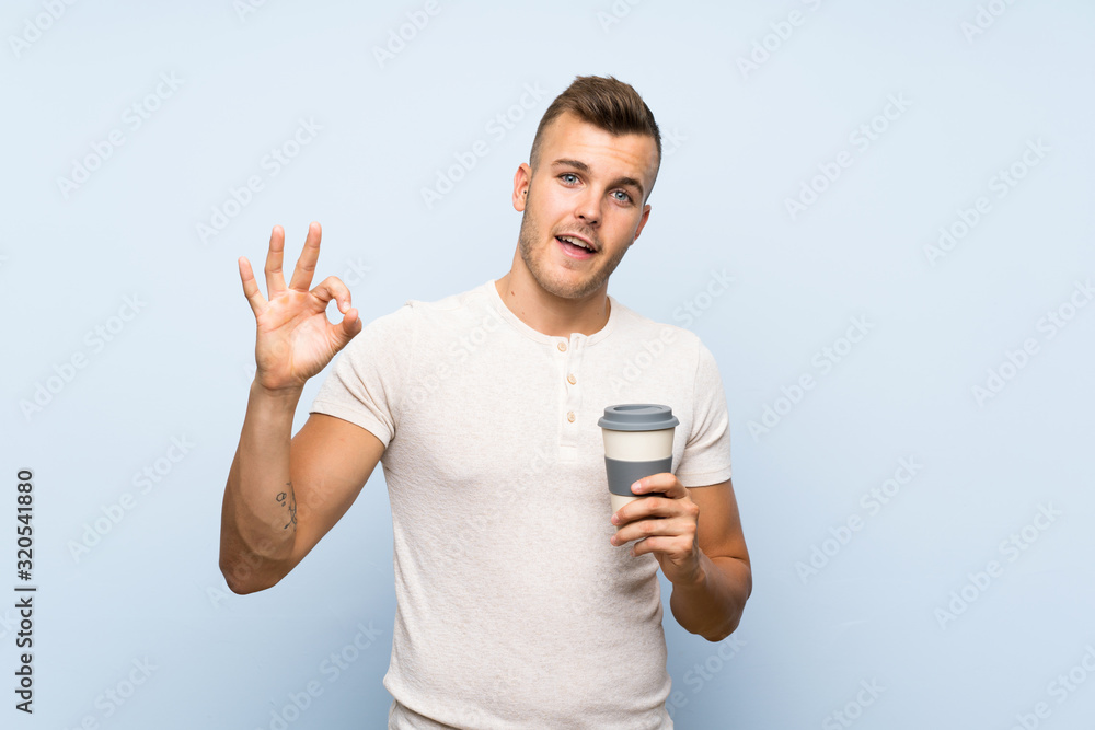 Young handsome blonde man over isolated blue background holding hot cup of coffee Young handsome blonde man over isolated blue background holding hot cup of coffee
