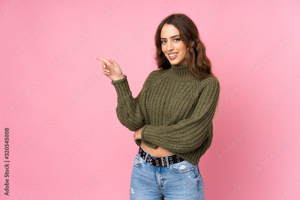 Young woman over isolated pink background pointing finger to the side Young woman over isolated pink background pointing finger to the side