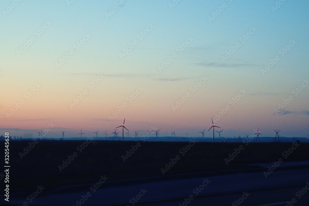 landscape with sunset and wind farm windmills after dark