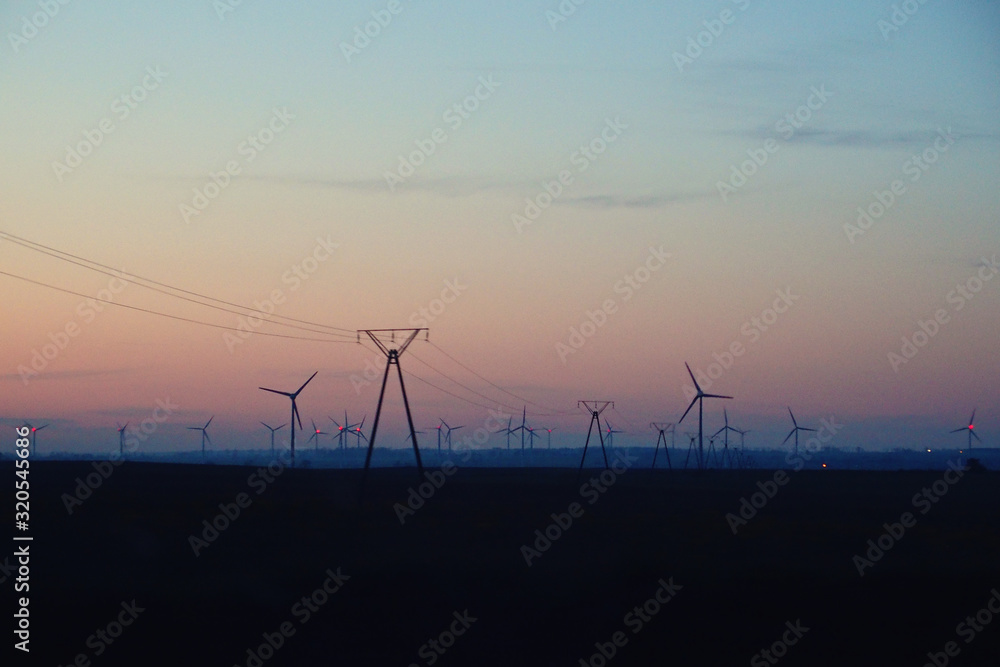 landscape with sunset and wind farm windmills after dark