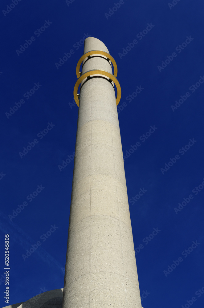 minaret of the cologne mosque with the two golden rings in front of bright blue sky minaret of the cologne mosque with the two golden rings in front of bright blue sky