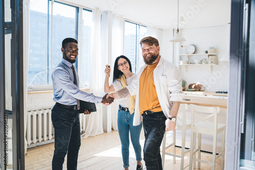 Black realtor and happy couple sealing deal by shaking hands photo