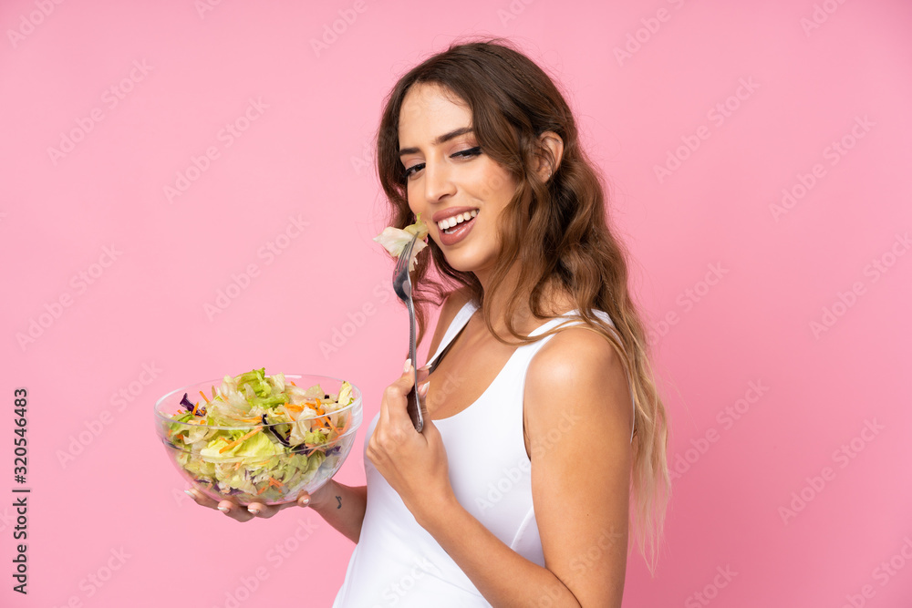 Young woman with salad over isolated pink wall Young woman with salad over isolated pink wall