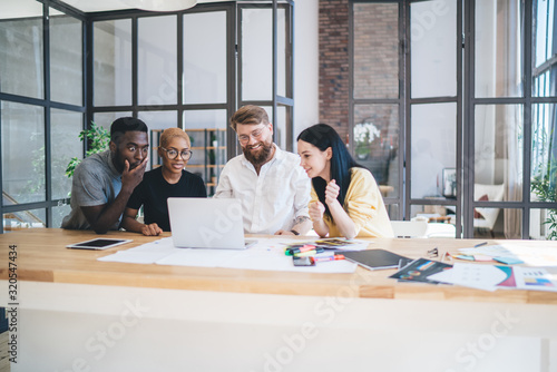 Group of anticipating multiethnic coworkers using laptop at office