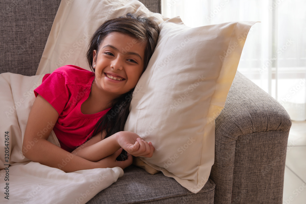 Young girl lying on the sofa with pillow and a blanket at home. (Children) Young girl lying on the sofa with pillow and a blanket at home. (Children)
