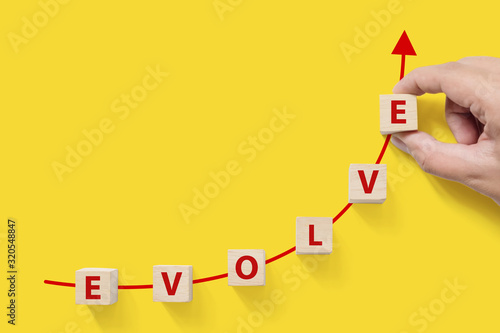 Wooded cube block on yellow background with word EVOLVE and copy space for your text