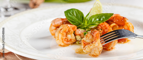 Spanish, Italian cuisine. King prawns with sauce. Serving dishes in a restaurant on a white plate, next to a glass of white wine. background image, copy space text
