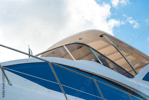 Nautical background of a row of luxury yachts, with black tinted windows and chrome metal railings on white fiber glass bows © Denis Starostin