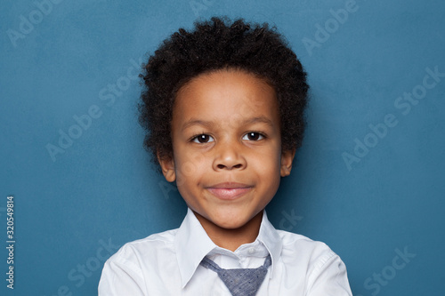 Curious black child schoolboy student portrait on blue background