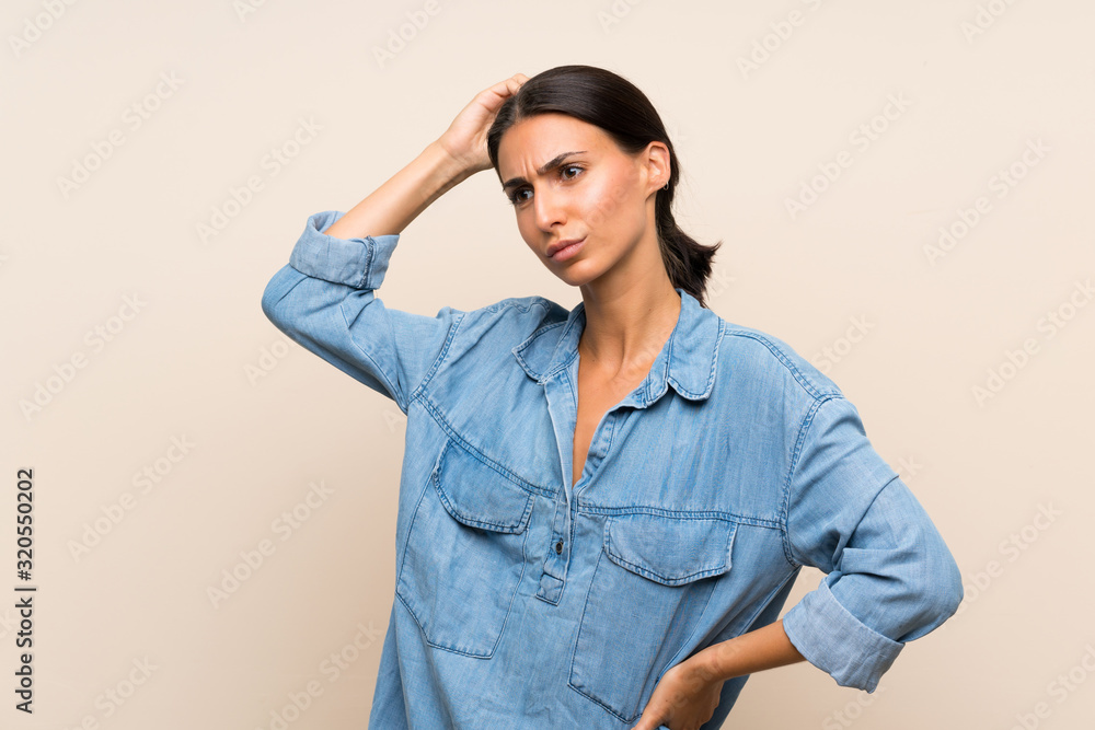 Young woman over isolated background having doubts while scratching head Young woman over isolated background having doubts while scratching head