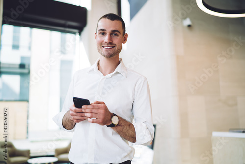 Joyful male using phone in office