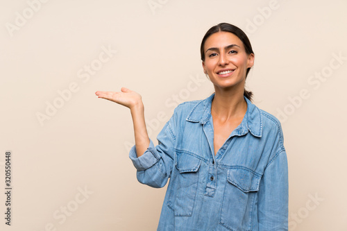 Young woman over isolated background holding copyspace imaginary on the palm to insert an ad