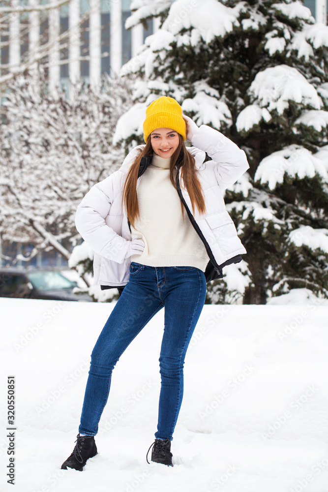 Full-length portrait of a young cheerful woman in a white down jacket Full-length portrait of a young cheerful woman in a white down jacket